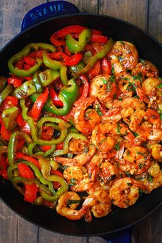 shrimp and peppers in a skillet on a wooden table