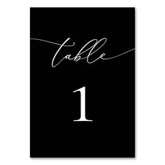 a black table number card with the word table 1 in cursive writing on it