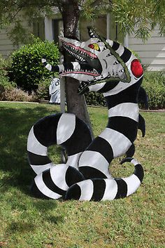 a black and white striped dragon statue in front of a house with a tree on the lawn