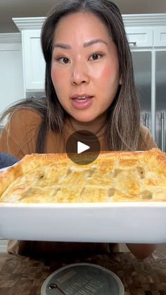 a woman is holding up a large casserole in front of her face and looking at the camera