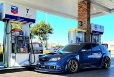 a blue car parked in front of a gas station