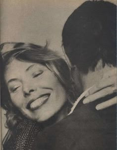 black and white photograph of woman hugging man's head with eyes closed in front of him