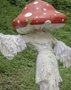 a red mushroom with white dots on it's head and skirt is standing in the grass