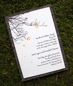 a wedding card laying on the ground in the grass with trees and leaves painted on it