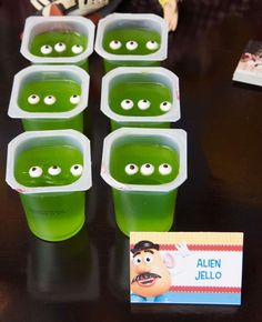 green jello cups with googly eyes are sitting on a table next to a card