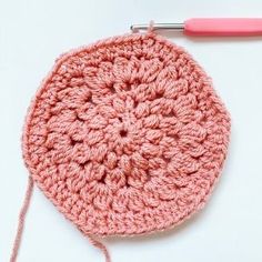 a crochet potholder is shown with a pink knitting needle