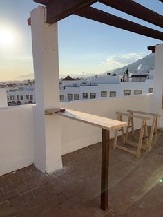 two wooden benches sitting on top of a roof next to a white building with mountains in the background