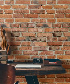 an old brick wall with a wooden desk in front of it and a camera on the table