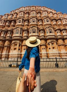 two people holding hands in front of a large building