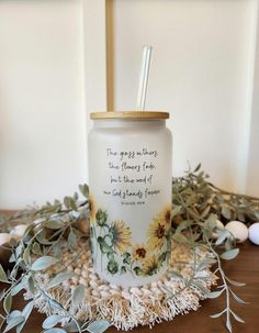 a glass with a straw in it sitting on a table next to eggs and greenery