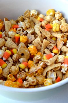 a white bowl filled with candy corn and cheetos cereal mix on top of a table