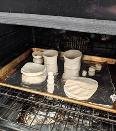 the oven is filled with white dishes and cups