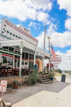 the outside of a small restaurant with an american flag on it's roof and sign in front