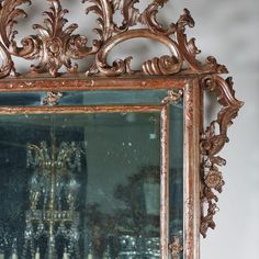 an ornate gold framed mirror hanging on the wall