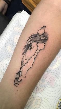 a woman's arm with a horse tattoo on the left side of her leg