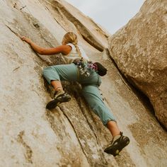 a woman climbing up the side of a large rock