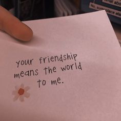 a hand holding a piece of paper that says your friend means the world to me