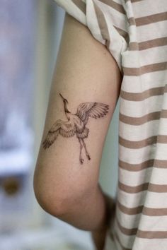 a woman with a small tattoo on her arm that has a bird flying over it