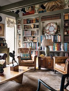 a living room filled with lots of furniture and bookshelves full of books on top of them