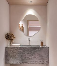 a bathroom sink with a mirror above it and a vase on the counter next to it