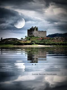 a castle sitting on top of a hill next to the ocean under a cloudy sky