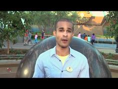 a man in a blue shirt is sitting on a giant chair and talking to someone