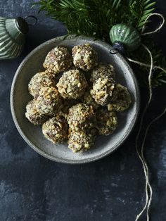 a white bowl filled with balls of food next to christmas decorations and greenery on a dark surface