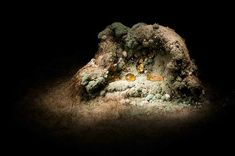 an image of some rocks in the dark with light coming from them and yellow glass bottles on top