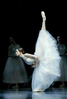 the ballerina is dancing with her arms stretched out in front of her and other dancers behind her