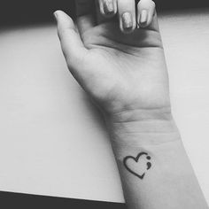 a woman's hand with a small heart tattoo on the middle of her wrist