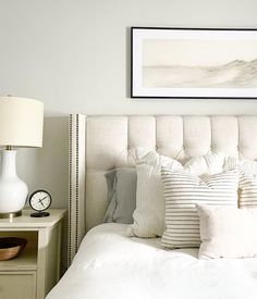 a bed with white linens and pillows in a small room next to a lamp