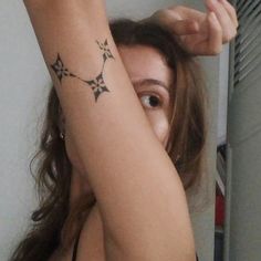 a woman with a tattoo on her arm is looking at the mirror and holding her hand up to her head