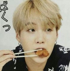 a person holding chopsticks in front of their mouth with food on it's tongue