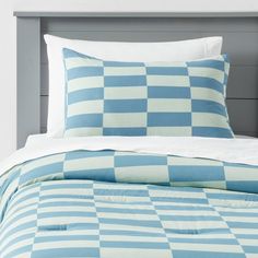 a blue and white checkered comforter set on a bed with two pillow cases