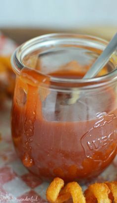 a glass jar filled with sauce and cheetos on top of a checkered table cloth