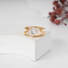 a gold ring with a white diamond in it sitting on top of a white box