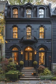 a large black house with many windows and steps leading up to the front door,