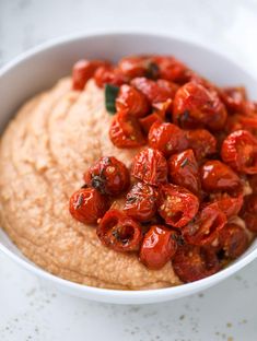 a white bowl filled with hummus and tomatoes