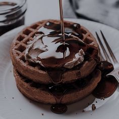 chocolate waffles with whipped cream on top and syrup drizzled over them