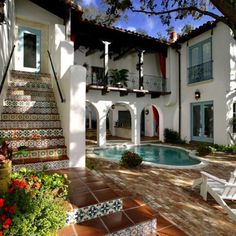 a house with a pool in the front yard and stairs leading up to it's second story