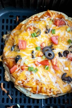 a pizza sitting on top of a grill covered in cheese and toppings