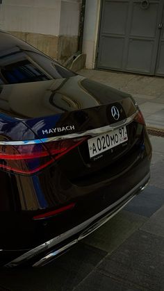 the rear end of a black car parked in front of a building