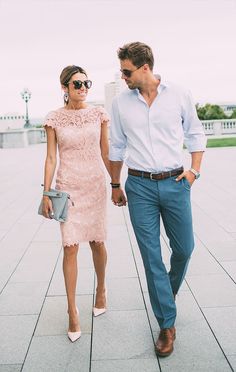 a man and woman walking down a sidewalk holding hands