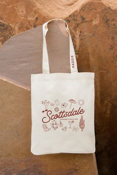 a white tote bag sitting on top of a stone wall