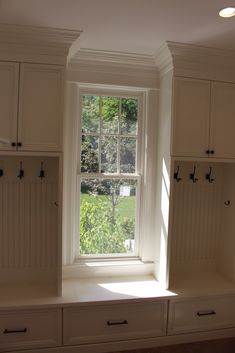 the sun shines through an open window in a room with white cabinets and drawers