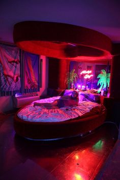 a large bed sitting in the middle of a room with red and purple lights on it