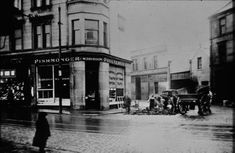 an old black and white photo of people in front of a store on a city street