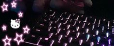 a person sitting at a computer keyboard with pink and blue lights on it's side