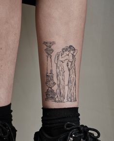 a woman's legs with a tattoo on her left leg, and a lamp post in the background