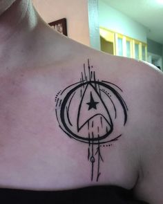 a woman's chest with a star trek symbol tattoo on her left side shoulder